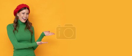 Photo for Very attractive young woman with awesome smile weared in red beret and green golf on orange background. - Royalty Free Image