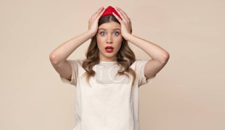 Téléchargez les photos : Shocked young woman in red beret on isolated light brown background. - en image libre de droit