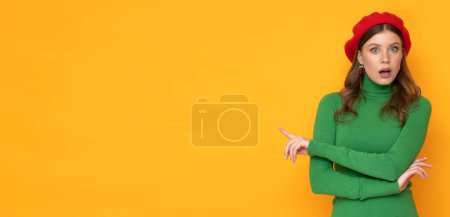 Photo for Shocked young woman with red beret and green sweater on isolated yellow background. - Royalty Free Image