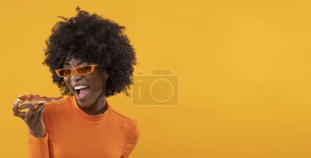 Téléchargez les photos : Heureuse femelle africaine avec tranche de pizza sur fond jaune isolé. - en image libre de droit