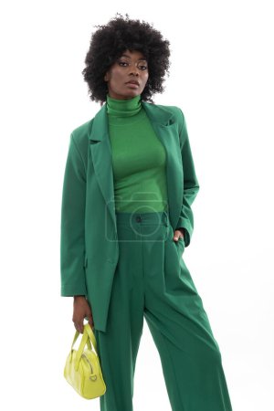 Foto de Morena de moda con traje verde y bolso de mano sobre fondo blanco aislado. - Imagen libre de derechos