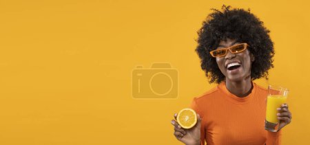 Photo for Happy woman is holding fresh orange juice on isolated orange background. - Royalty Free Image