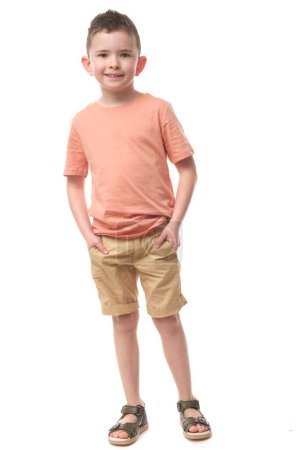 Téléchargez les photos : Joli jeune garçon en t-shirt pastel et short sur fond blanc isolé. - en image libre de droit