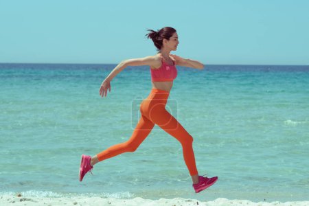 Photo for Beautiful woman jogging on the beach. Fashionable styling and retro colors! - Royalty Free Image