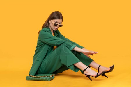 Téléchargez les photos : Modna modelka w duym zielonym Modèle féminin à la mode en costume vert surdimensionné sur fond jaune isolé. - en image libre de droit