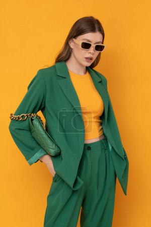 Foto de Modna modelka w duym zielonym Modelo femenino de moda en traje verde de gran tamaño sobre fondo amarillo aislado. - Imagen libre de derechos