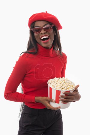 Téléchargez les photos : Une belle femme noire avec du pop-corn regarde un film. - en image libre de droit