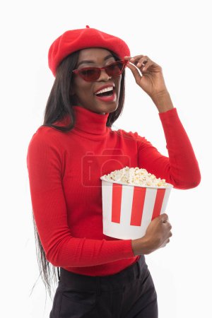 Foto de Una hermosa mujer negra con palomitas de maíz está viendo una película. - Imagen libre de derechos