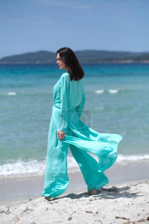 Foto de Hermosa morena en ropa turquesa en la playa. - Imagen libre de derechos