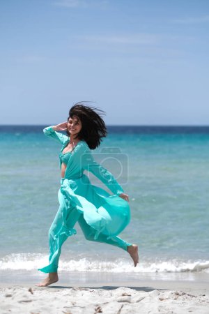 Téléchargez les photos : Belle brune en vêtements turquoise sur la plage. - en image libre de droit