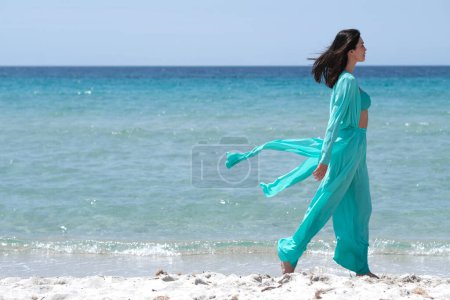 Téléchargez les photos : Belle brune en vêtements turquoise sur la plage. - en image libre de droit