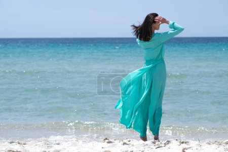 Photo for Beautiful brunette in turquoise clothes on the beach. - Royalty Free Image