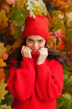 Foto de Hermosa morena en un paisaje de otoño con un sombrero rojo y bufanda. - Imagen libre de derechos