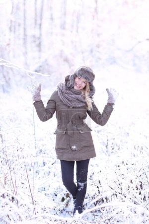 Téléchargez les photos : Fille blonde heureuse dans un paysage d'hiver avec un chapeau et des gants. - en image libre de droit