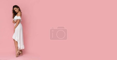 Téléchargez les photos : Très jolie jeune femme en robe blanche sur fond rose isolé. - en image libre de droit