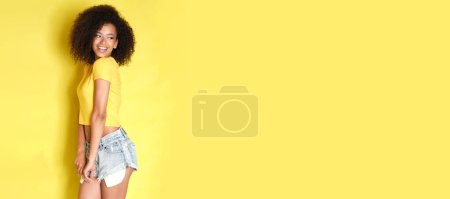 Téléchargez les photos : Femme mignonne avec des cheveux bouclés sur fond jaune. - en image libre de droit