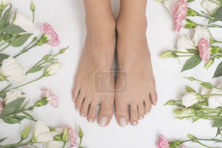 Foto de Hermosos pies femeninos con flores en el fondo. - Imagen libre de derechos