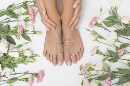 Téléchargez les photos : Beaux pieds féminins avec des fleurs en arrière-plan. - en image libre de droit