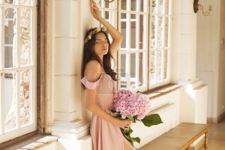 Foto de Hermosa mujer en un vestido largo con un ramo de flores en el interior de un palacio. - Imagen libre de derechos