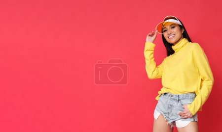 Foto de Hermosa mujer asiática en suéter amarillo sobre fondo rojo. - Imagen libre de derechos
