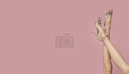 Foto de Patas femeninas delgadas sobre fondo rosa aislado. - Imagen libre de derechos