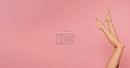 Foto de Patas femeninas delgadas y largas sobre un fondo rosa pastel. - Imagen libre de derechos