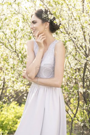 Téléchargez les photos : Belle brune dans une robe de mariée en fleurs d'arbres. - en image libre de droit