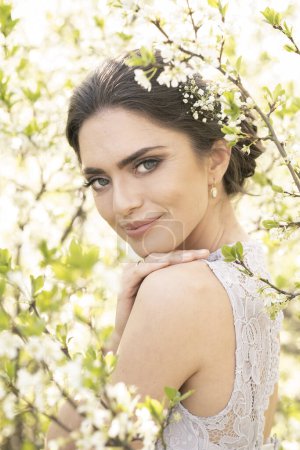 Téléchargez les photos : Belle brune dans une robe de mariée en fleurs d'arbres. - en image libre de droit