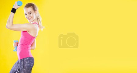 Positive fitness trainer on isolated yellow background.