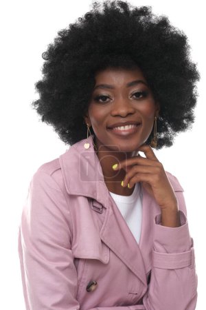 Téléchargez les photos : Plan studio d'une belle femme noire aux cheveux afro portant un manteau rose. - en image libre de droit
