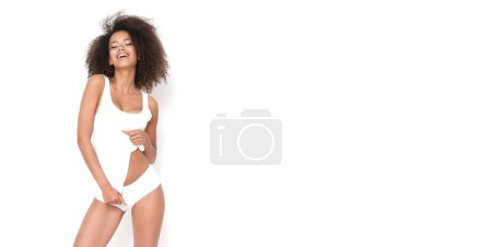 Foto de Mujer afroamericana feliz en camiseta blanca y bragas muestra su cuerpo en forma. - Imagen libre de derechos