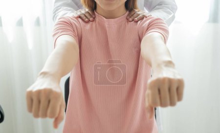 Téléchargez les photos : Les physiothérapeutes féminines fournissent une assistance physique aux patients souffrant de blessures aux épaules en massant leurs épaules pour la récupération musculaire dans le centre de réadaptation. Concepts de physiothérapie. - en image libre de droit