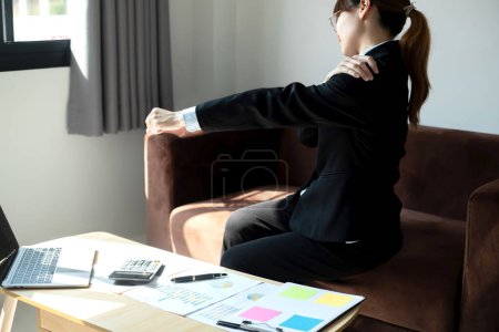 Asiática contable mujer está cansada de trabajar en una silla, estiramiento para relajarse y relajarse mientras trabaja duro en la oficina.