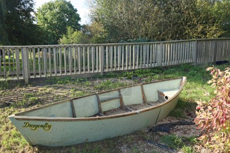 Photo for An old abandoned canoe by a wooden fence in the public park in Langport, Somerset - Royalty Free Image