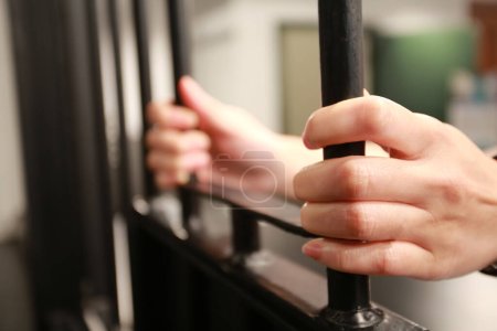 Téléchargez les photos : Femme jeune Main tenant la fenêtre de la prison - en image libre de droit