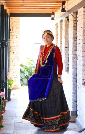 a villager girl dressing in Gurung traditional dressing walk down the staircase and look at camera 
