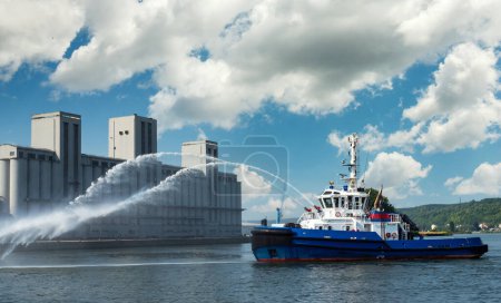 A firefighter floating modern tug boat sprays jets of water