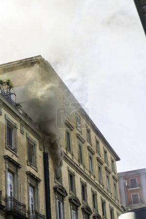 Photo for Naples, Italy - February 15th 2023 - Domestic apartment fire with smoke billowing from upstairs window. Garibaldi Square, Naples, Italy, portrait - Royalty Free Image