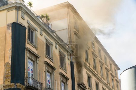 Photo for Naples, Italy - February 15th 2023 - Domestic apartment fire with smoke billowing from upstairs window. Garibaldi Square, Naples, Italy, landscape - Royalty Free Image