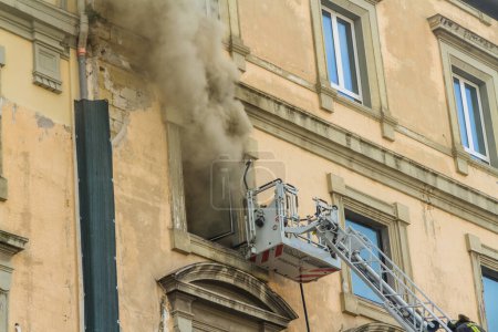 Photo for Naples, Italy - February 15th 2023 - Domestic apartment fire with smoke billowing from window. Garibaldi Square, Naples, Italy. Magirus Fire engine basket or cage. - Royalty Free Image