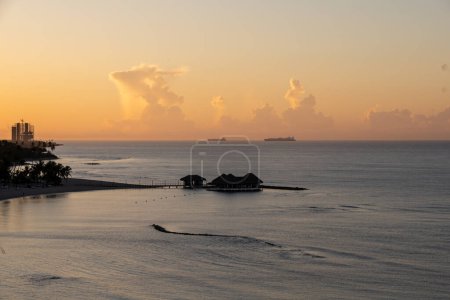 Photo for Juan Dolio, Dominican Republic, 17 august 2022. Wide angle shot from above of a series of bungalows in the tranquil caribbean sea. Sweet sunrise or sunset light. - Royalty Free Image