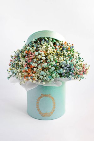 Multi-colored gypsophila in a box on a white background close-up with a blurred background. Airy bouquet of gypsophila flowers