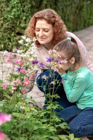 Photo for Mom and daughter walk in the park and look at flowers. Allergy. - Royalty Free Image