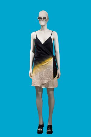 Foto de Imagen de longitud completa de un maniquí de exhibición femenina con vestido de verano de moda con correas de hombro aisladas sobre fondo azul - Imagen libre de derechos