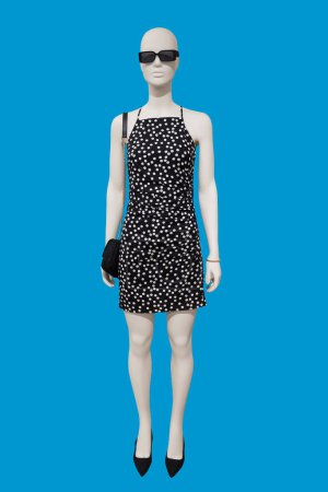 Foto de Imagen de longitud completa de un maniquí de exhibición femenina que lleva un vestido de lunares negro de moda aislado sobre fondo azul - Imagen libre de derechos
