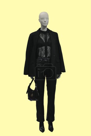 Téléchargez les photos : Image pleine longueur d'un mannequin femme portant une veste déboutonnée noire tendance et un pantalon en cuir isolé sur fond jaune - en image libre de droit
