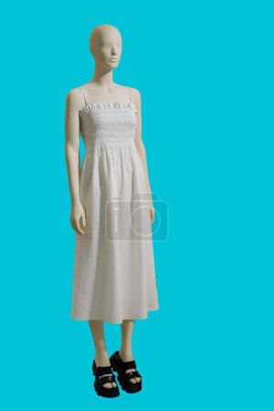 Foto de Imagen de longitud completa de un maniquí femenino con vestido de verano blanco de moda con tirantes aislados sobre fondo azul - Imagen libre de derechos
