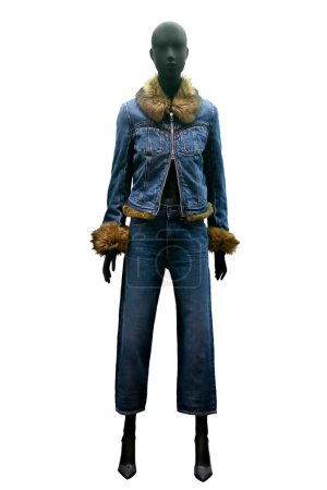Full length image of a female display mannequin wearing blue denim suit, denim jacket with fur collar and cuffs and trousers isolated on white background