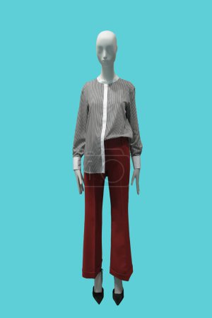 Full length image of a female display mannequin wearing striped collarless shirt and red trousers Isolated on blue background