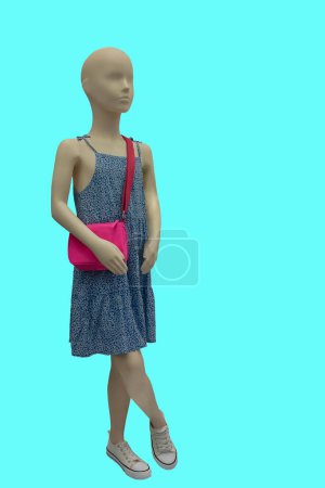 Full length image of a child display mannequin wearing beautiful colorful sleeveless dress isolated on blue background